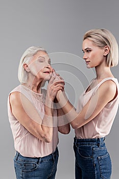 Emotional short-haired senior woman petting beautiful daughter