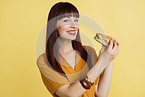 Emotional smiling happy beautiful red haired pretty woman in yellow blouse on yellow studio background, holding fresh