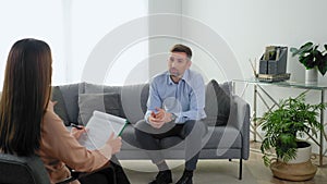 Emotional smiling man patient with mental health problem talking to therapist