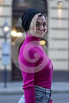 Emotional street portrait of a blonde woman 35-40 years old, a hipster in a hat on a blurry background of evening city showcases,