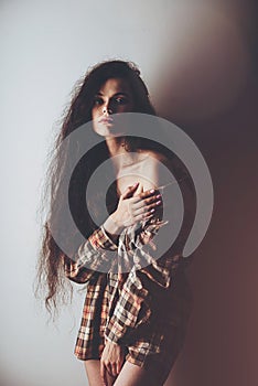 Emotional studio portrait of a young woman in a wireless headphones and checkered shirt
