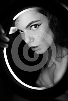 Emotional studio portrait of a young woman in a wireless headphones with ring flash effect. Round LED Circle Lamp.