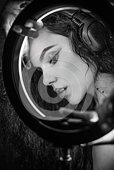 Emotional studio portrait of a young woman in a wireless headphones with ring flash effect. Round LED Circle Lamp.