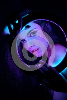 Emotional studio portrait of a young woman in a wireless headphones with ring flash effect. Round LED Circle Lamp.