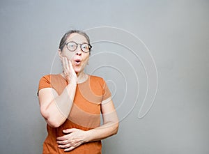 Emotional surprised middle-aged woman on   gray background