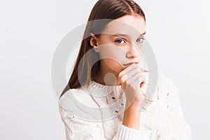 Emotional teen girl in a white knitted sweater on a light gray background.Space for text.