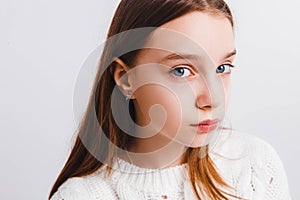 Emotional teen girl in a white knitted sweater on a light gray background.Space for text.