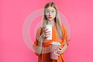 Emotional teenage girl with popcorn and beverage during cinema show