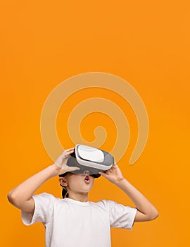 Emotional teenager enjoying virtual reality on orange background