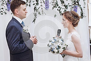 Emotional wedding moment - sensual bride taking vows with happy groom at wedding ceremony aisle with bouquet
