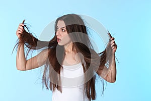 Emotional woman with damaged hair on color background.