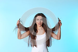 Emotional woman with damaged hair on color background