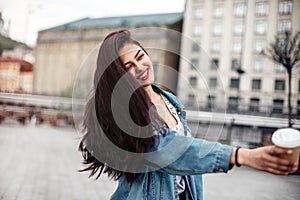 Emotional woman with an elegant hairstyle laughs while walking down the street Outdoor portrait of a dark-haired young woman in a