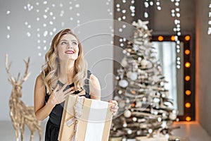 Emotional woman gets a valuable gift surprise. The girl in a black dress is rejoicing. Concept of Happy Christmas and New Year, w