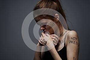 Emotional woman with inscriptions on body upset with frustration gray background