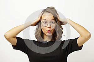 Emotional woman in shock puts her hands to head, pulls lips with tube, wide open eyes, shows surprise and shock on white