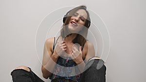 Emotional woman singing. Female in headphones with bright makeup singing the song on white background. Girl listening music in hea