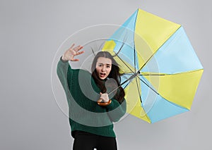 Emotional woman with umbrella caught in gust of wind on grey background
