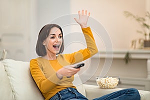 Emotional woman watching TV show with popcorn at home