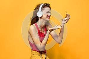 Emotional woman wearing headphones listen to music close-up yellow background