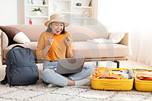 Emotional young asian woman traveler using laptop at home