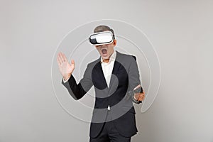 Emotional young business man looking in headset, playing video game with joystick, keeping mouth wide open isolated on