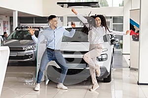 Emotional young couple dancing in car saloon, holding key