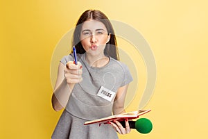 Emotional young girl, female reporter holding reporter microphone isolated on yellow studio background. Concept of