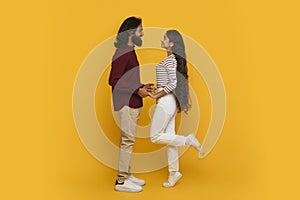 Emotional young indian couple have date, yellow background