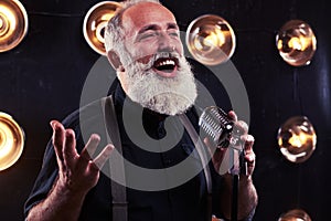 Emotional young man holding a retro silver studio microphone in