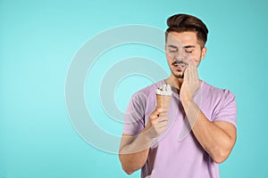 Emotional young man with sensitive teeth and ice cream on color background.