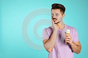 Emotional young man with sensitive teeth and ice cream on color background. photo