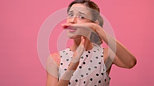 Emotional young woman asking for timeout on pink wall background.