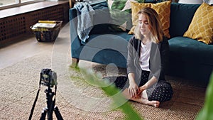 Emotional young woman blogger is recording video for her internet vlog talking and looking at professional camera. Girl
