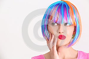 Emotional young woman with colorful hair on light background