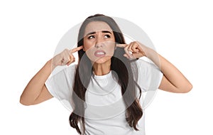 Emotional young woman covering ears with fingers on white background