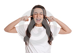 Emotional young woman covering ears with fingers on white background