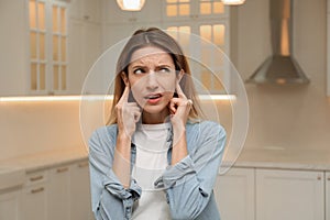 Emotional young woman covering her ears with fingers at home