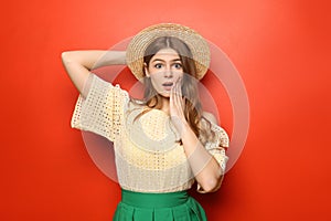 Emotional young woman with hat on color background