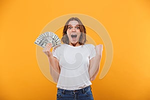 Emotional young woman holding money make winner gesture.