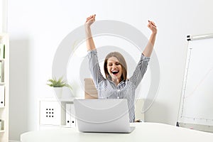 Emotional young woman with laptop celebrating victory photo