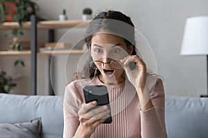 Emotional young woman looking at smartphone screen with opened mouth.