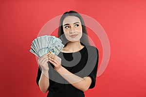 Emotional young woman with money on background