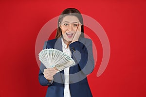 Emotional young woman with money on background