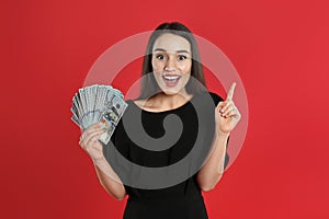 Emotional young woman with money on crimson background