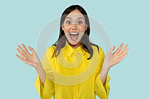 Emotional young woman showing amazement on blue background