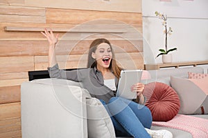 Emotional young woman with tablet celebrating victory