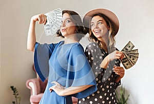 Emotional young women indoors holding money.