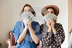 Emotional young women indoors holding money.