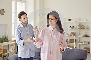 Emotionally stressed young couple arguing angrily at home during family conflict.